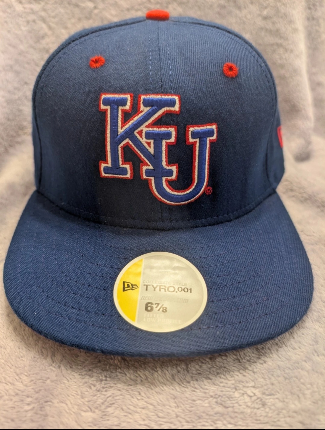 A navy New Era Tyro.001 fitted cap for the Kansas Jayhawks with a red-outlined KU logo, its factory sticker reading Collegiate Style Tyro.001, size 6 7/8